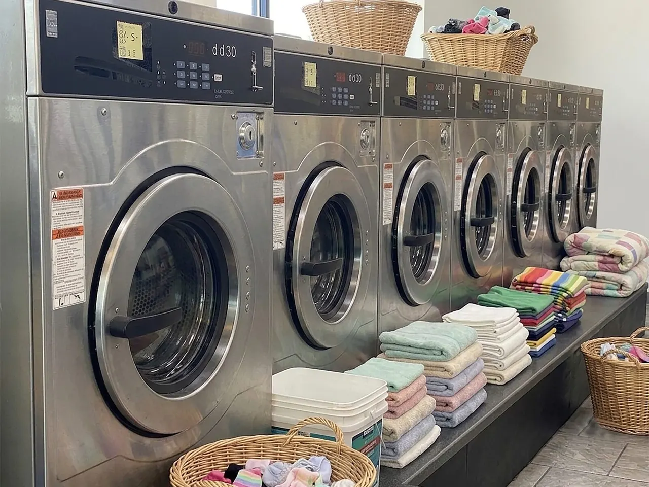 Row of washing machines and folded laundry at Jasmin Express in Barnet